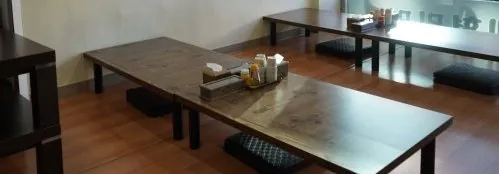 좌식 나무 탁자와 방석이 놓인 홀, 오른쪽 창가 자리까지
