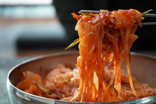 빨간 양념에 비빈 면을 젓가락으로 들어 올린 모습