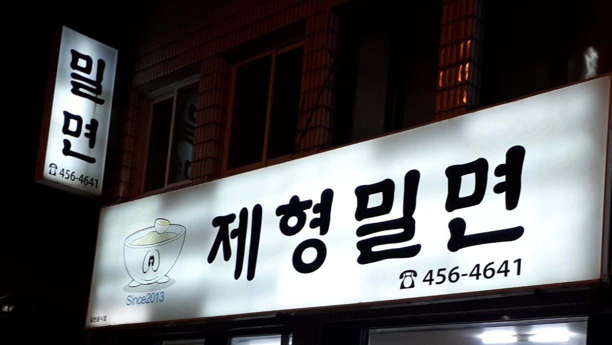 밤에 불 켜진 제형밀면 간판과 세로 간판 «밀면»