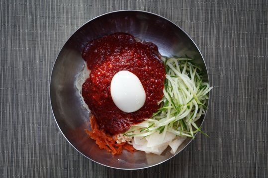 위에서 본 비빔밀면 — 국물 없이 빨간 양념장 듬뿍, 삶은 달걀, 오이채, 당근채, 무