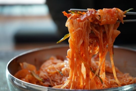 빨간 양념에 비빈 면을 젓가락으로 들어 올린 모습